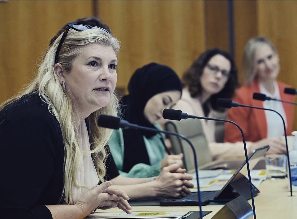 Dr Gabrielle Morrissey speaking at a roundtable of panelists with table microphones